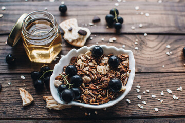 Healthy breakfast ingredients. Homemade granola, oatmeal, yogurt in the bottle, honey, berries and fruits on a wooden background. Morning aesthetics and beautiful layout on a wooden table.