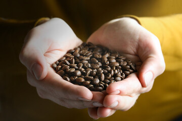 Close up of Mans hands holding roasted coffee beans. High quality photo.