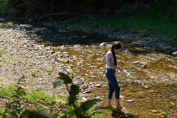 Naklejka na ściany i meble Young brunette bare woman walks along mountain river
