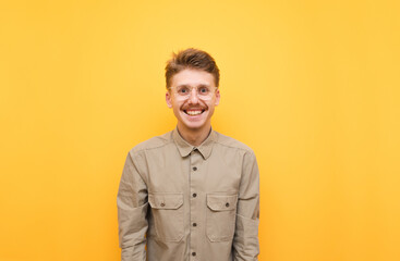 Portrait of happy guy in shirt, glasses and mustache on yellow background, looking at camera and smiling. Cheerful geek isolated on yellow background. Copy space