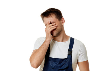 sad caucasian worker repairman in blue overalls isolated on white studio background.