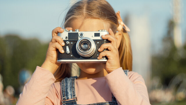 Little girl with a retro camera outdoors