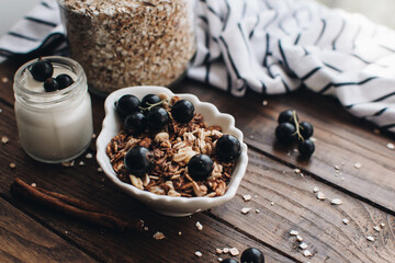 Healthy breakfast ingredients. Homemade granola, oatmeal, yogurt in the bottle, honey, berries and fruits on a wooden background. Morning aesthetics and beautiful layout on a wooden table.