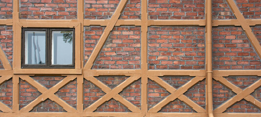 Pattern of traditional half-timbered house wall with red brick and window - 366915497