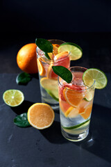Health care, fitness, healthy nutrition diet concept. Fresh cool homemade citrus infused detox water with grapefruit, orange, lemon and lime and ice in glasses on dark background.