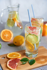 Health care, fitness, healthy nutrition diet concept. Fresh cool homemade citrus infused detox water with grapefruit, orange, lemon and lime and ice in a jug and glasses for spring summer days.