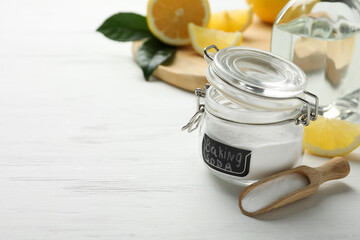Baking soda, vinegar and cut lemons on white wooden table. Space for text