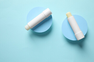 Hygienic lipsticks on turquoise background, flat lay
