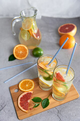 Health care, fitness, healthy nutrition diet concept. Fresh cool homemade citrus infused detox water with grapefruit, orange, lemon and lime and ice in a jug and glasses for spring summer days.