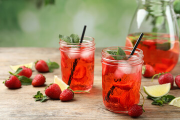 Refreshing drink with strawberry and lime on wooden table