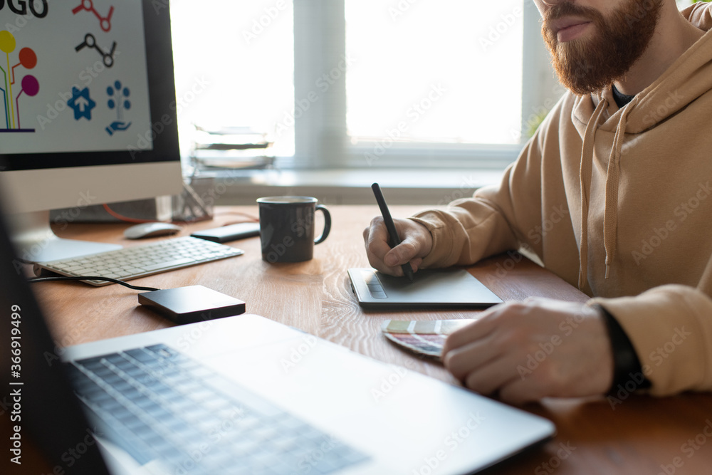 Wall mural close-up of busy brand designer sitting at desk and creating graphic design using digitizer and colo