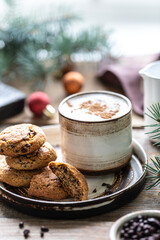 Homemade cookies with nuts and coffee in a ceramic cup on a wooden table with toys and Christmas tree branches