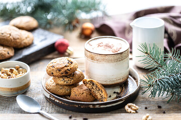 Homemade cookies with nuts and coffee in a ceramic cup on a wooden table with toys and Christmas tree branches