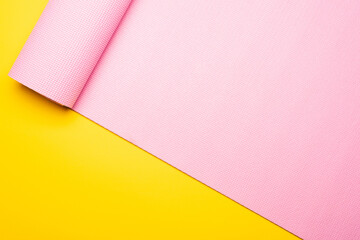 top view of pink fitness mat on yellow background