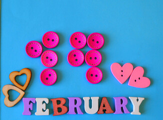 Fototapeta premium 14 February inscription made of wooden buttons against blue background, Saint Valentine's greeting card. DIY 