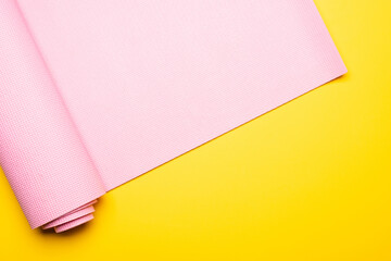 top view of pink fitness mat on yellow background