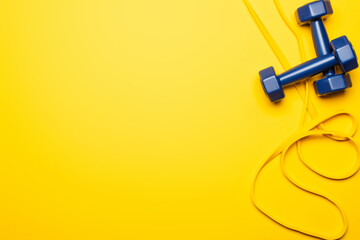 top view of blue dumbbells and resistance band on yellow background