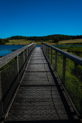 Fototapeta na wymiar wooden jetty going out over lake in summer ,Lozere , france . with blue sky