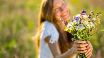 Beautiful woman with wildflower over natural background