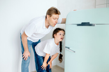 father and daughter emotionally look into the refrigerator in search of delicious food, spending time together at home