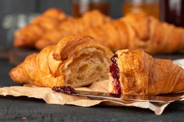 Fresh croissants with berry jam on dark wooden board