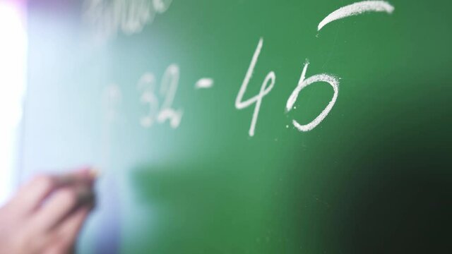 The teacher writes a math example on the school board. Math lesson. Distance learning for children. The teacher conducts an online lesson. E-learning. Homeschooling