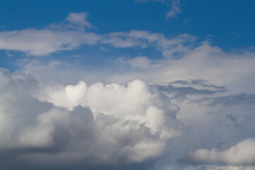 White, dark gray cumulus clouds. Blue sky. Natural background.