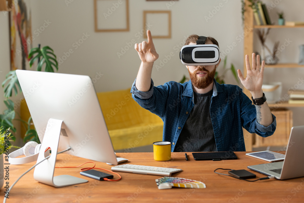 Wall mural young bearded man touching invisible screen while working on virtual design in virtual reality heads