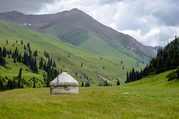 Fototapeta na wymiar Kazakh traditional yurt in green mountains. Outdoor camping in traditional yourt concept. Travel in Kazakhstan.