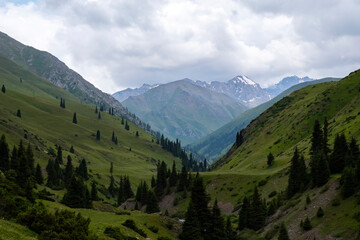 Green mountain valley with clouds. Adventure travel. Outdoor landscape. Summer vacation travel concept. Kazakhstan mountains, Tekes river valley. Tourism in Kazakhstan concept.