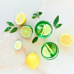 Tasty lemonade or mojito cocktail with lemon and lime. Refreshing drink or beverage. Colorfull backdrop with fruits and berries