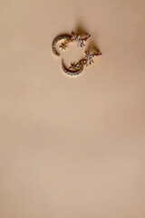 Fashionable gold earrings on pastel peach background. Selective focus.