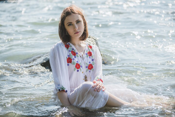 Young woman in white dress enjoys sea.