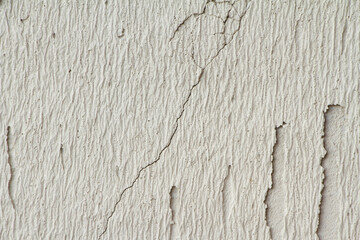 Cracked plastered wall. Background of gray old concrete wall. Decorative embossed concrete and glue plaster.