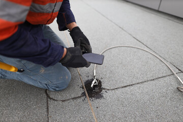 Inspector auditor technician using his phone photographing fall arrest, fall restraint roof anchor...