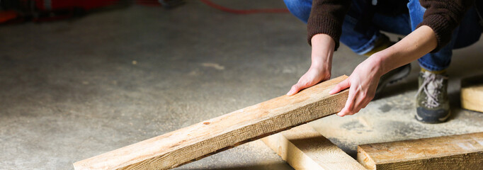 Carpenter builder holding wooden plank at his workstation. 