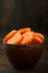 Sliced carrots in a bowl on a wooden background. Vegetable, ingredient and staple food.