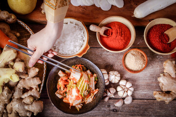 Girl wearing hanbok, holding chopsticks to taste kimchi In a tile bowl. Concept of Korean Fermented Cooking. Top view