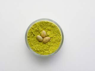 Pistachio flour in a glass bowl on a white background. Shredded pistachios.