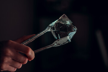 hand holding ice to cocktail