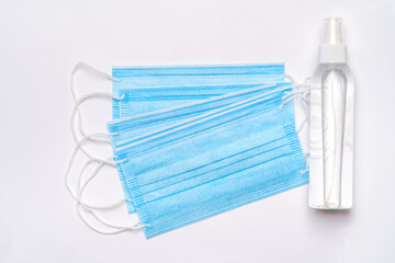 bottle of lotion, sanitizer or liquid soap and medical protective mask isolated on light grey background