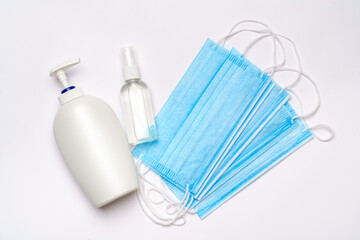 bottle of lotion, sanitizer or liquid soap and medical protective mask isolated on light grey background