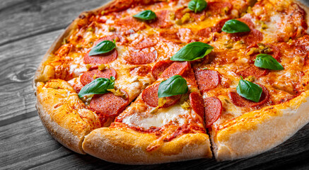 Pepperoni Pizza with Mozzarella cheese, salami, Tomato sauce, pepper, Spices and Fresh basil. Italian pizza on wooden table background