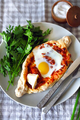 Selective focus. Macro. Khachapuri with egg and herbs on a plate.