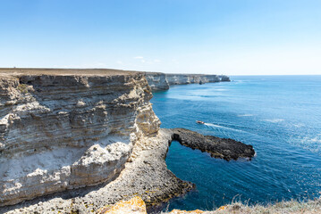 Obraz premium Beautiful view of blue sea and mountain. Calm water in bay with rock, sunny day, boat with people
