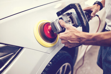 Car detailing - Hands with orbital polisher in auto repair shop. Selective focus.