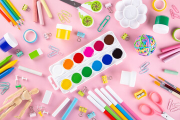 Various school office and painting supplies on pink background. Back to school concept. Top view. Copy space