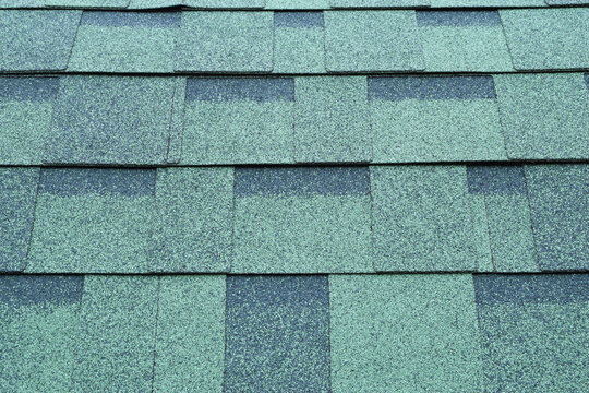 New green asphalt roof shingles textured surface as abstract industrial background.
