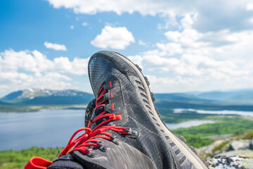 Hiking boot closeup with summer scenery view outdoors in the wilderness.