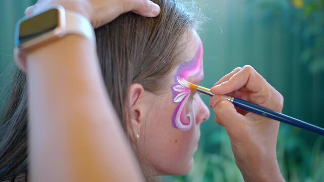 Artist drawing on face teenager girl, preparing for carnival